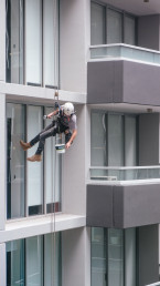 window cleaner working suspended next to a building